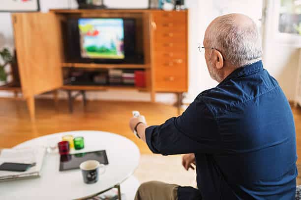 Personne âgée qui regarde la télévision dans son salon adapté aux seniors