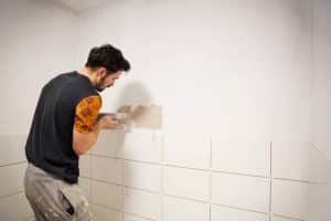 Homme en train de poser des carreaux blancs muraux