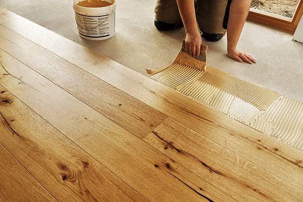 Personne qui pose du parquet avec de la colle