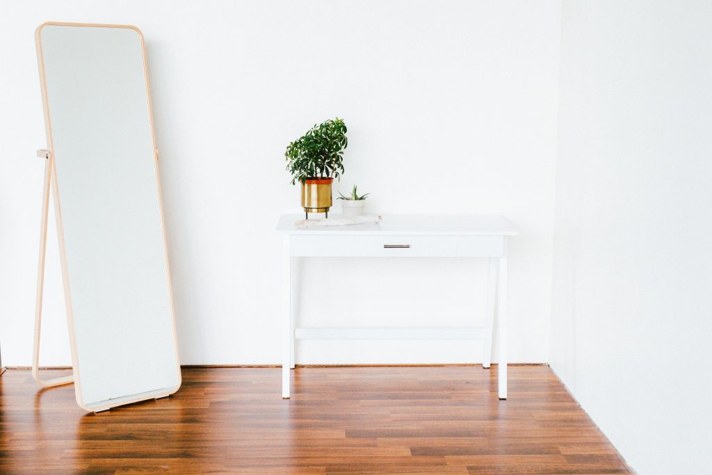 Petite commode et grand miroir dans une chambre blanche