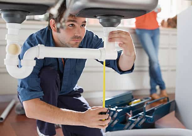 Plombier en train de nettoyer une canalisation dans une cuisine