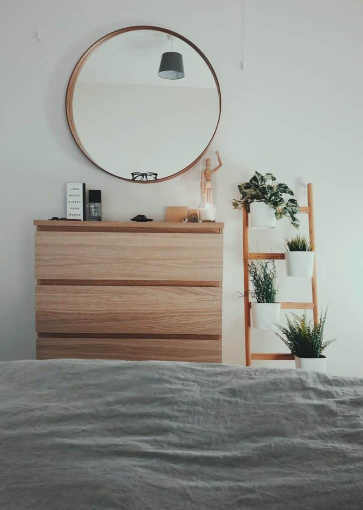 Chambre avec meuble en bois, miroir mural et plantes vertes