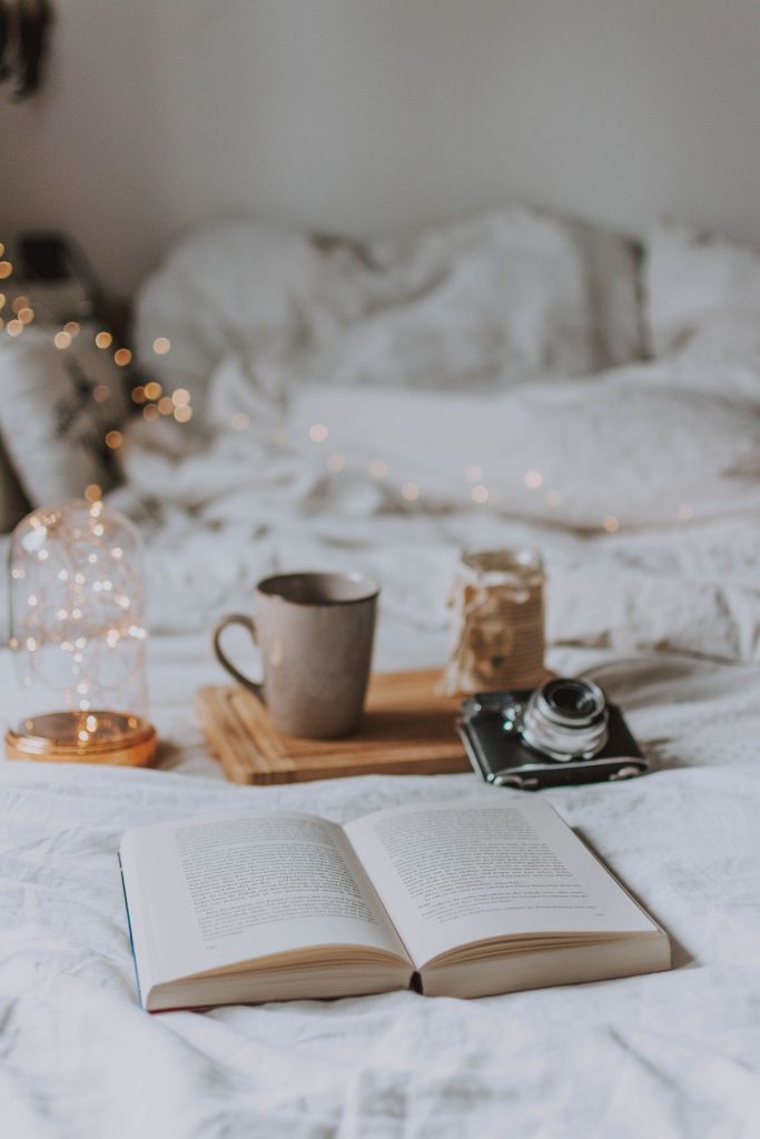 Tasse, appareil photo et livre sur un lit