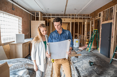 deux personnes qui regardent les plans dans une maison en construction